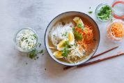 Essstäbchen und Schale mit asiatischer Reisnudelsuppe, gevierteltes Ei und Gemüse Essstäbchen und Schale mit asiatischer Reisnudelsuppe, gevierteltes Ei und Gemüse